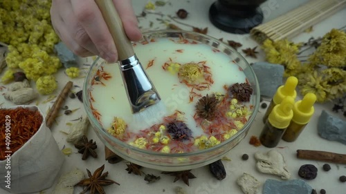 Woman's hand mixes natural ingredients in a glassware in slow motion. Preparation of domestic cosmetics. Alternative medicine, organic cosmetics, aromatherapy and natural care concept.