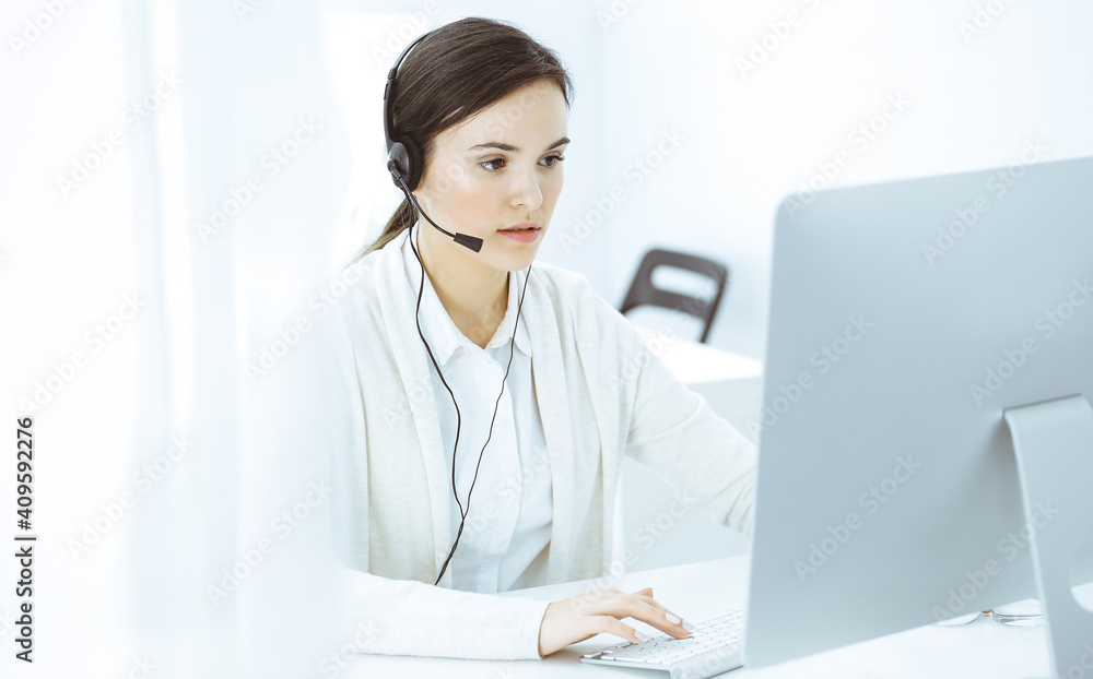 Call center. Casual dressed woman sitting in headset at customer service office. Group of operators at work. Business concept Call center. Casual dressed woman sitting in headset at customer service office. Group of operators at work. Business concept