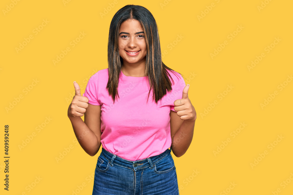Young latin girl wearing casual clothes success sign doing positive gesture with hand, thumbs up smiling and happy. cheerful expression and winner gesture. Young latin girl wearing casual clothes success sign doing positive gesture with hand, thumbs up smiling and happy. cheerful expression and winner gesture.