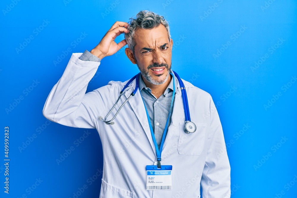 Middle age grey-haired man wearing doctor uniform and stethoscope confuse and wonder about question. uncertain with doubt, thinking with hand on head. pensive concept. Middle age grey-haired man wearing doctor uniform and stethoscope confuse and wonder about question. uncertain with doubt, thinking with hand on head. pensive concept.
