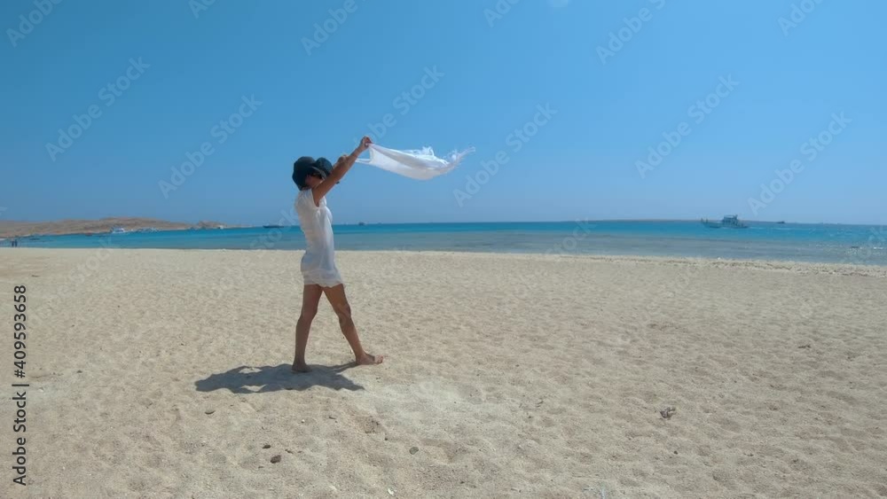 Beautiful young woman walk in slow motion holding fabric pareo sarong waving at wind in a summer vacation. freedom concept. Tourist on Giftun islands, Egypt Beautiful young woman walk in slow motion holding fabric pareo sarong waving at wind in a summer vacation. freedom concept. Tourist on Giftun islands, Egypt