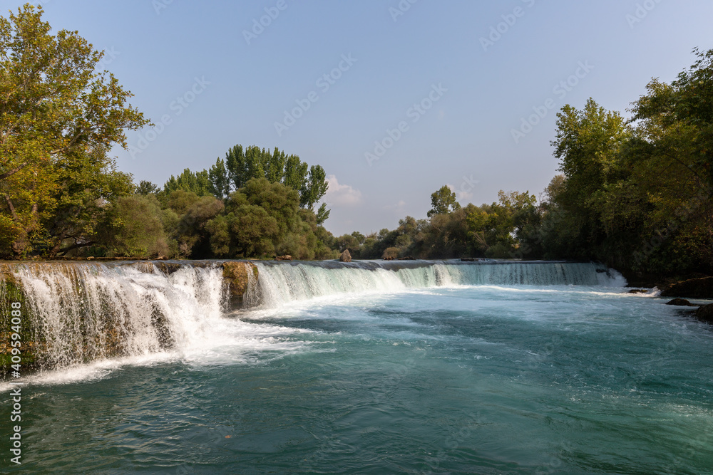 Fototapeta premium Big waterfall in the forest and empty blue sky