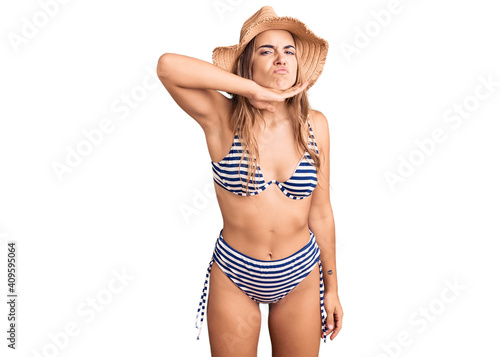 Young beautiful blonde woman wearing bikini and hat cutting throat with hand as knife, threaten aggression with furious violence © Krakenimages.com