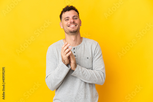 Young caucasian handsome man isolated on yellow background applauding after presentation in a conference