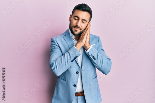 Young hispanic businessman wearing business jacket sleeping tired dreaming and posing with hands together while smiling with closed eyes.