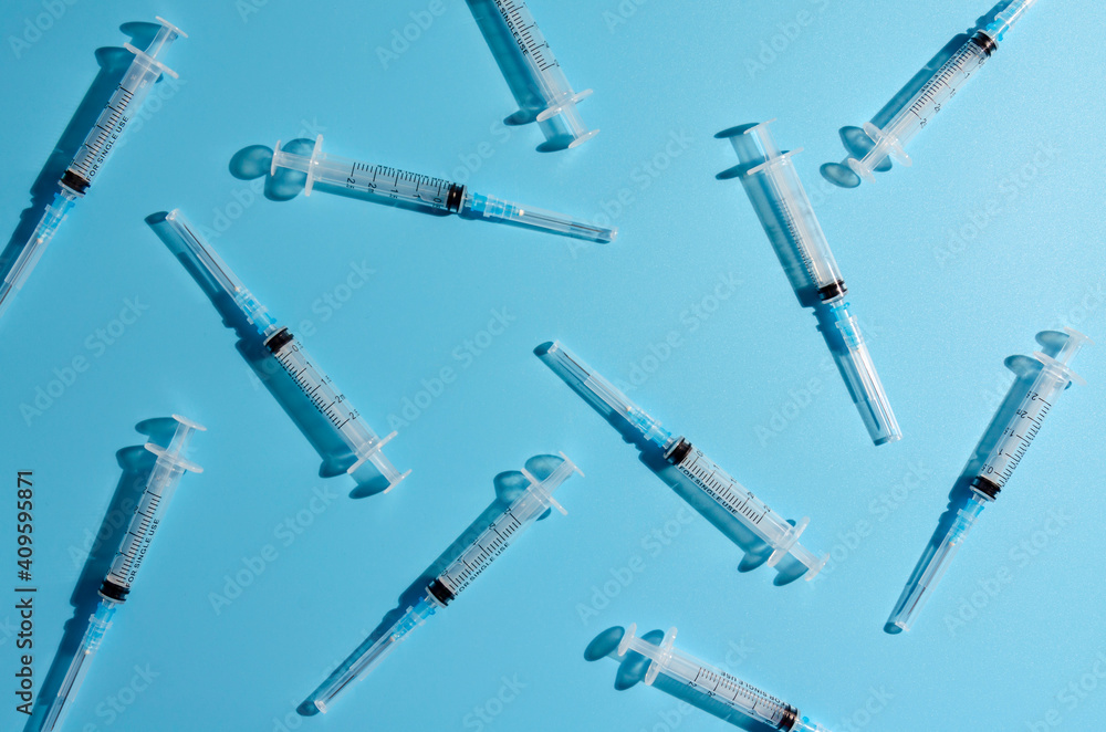 plastic syringe on a blue background with shadow. plastic syringe on a blue background with shadow.