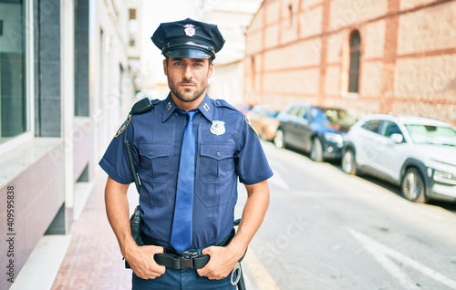 Fototapeta young handsome hispanic policeman wearing police uniform
