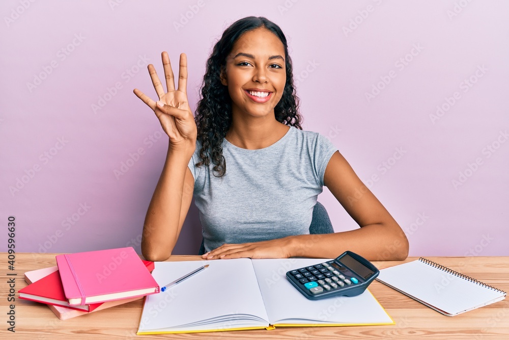 Young african american girl accountant working at the office showing and pointing up with fingers number four while smiling confident and happy. Young african american girl accountant working at the office showing and pointing up with fingers number four while smiling confident and happy.