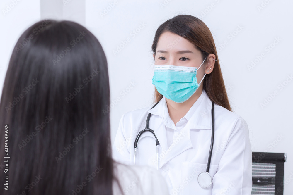 Asian woman doctor is talking with her patient to consult and check symptom which wears medical face mask always diagnostic in new normal and health care concept. Asian woman doctor is talking with her patient to consult and check symptom which wears medical face mask always diagnostic in new normal and health care concept.