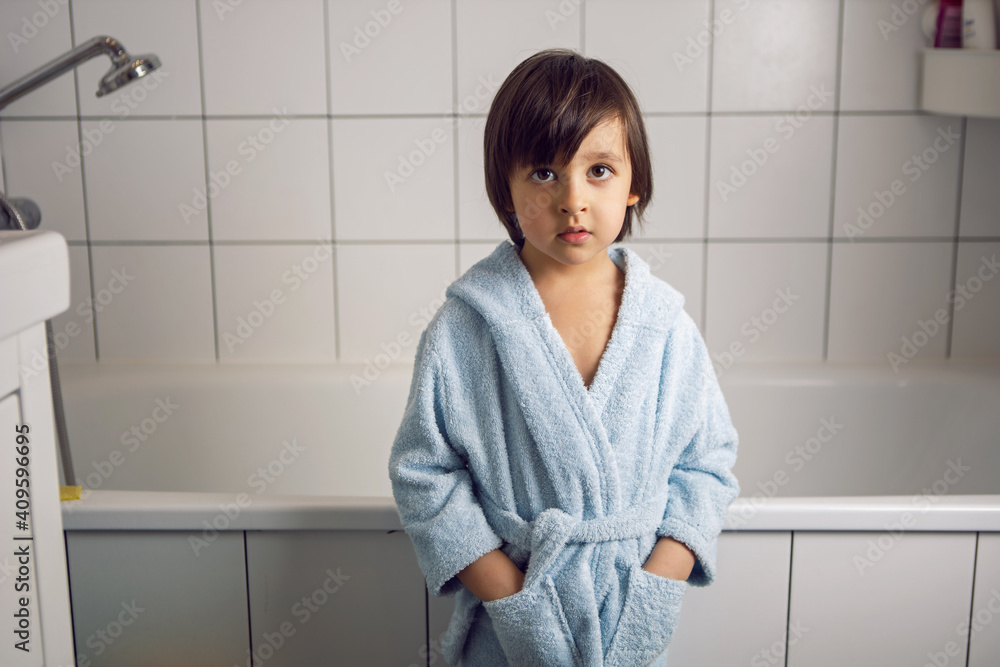 boy in a blue bathrobe stands in the bathroom boy in a blue bathrobe stands in the bathroom
