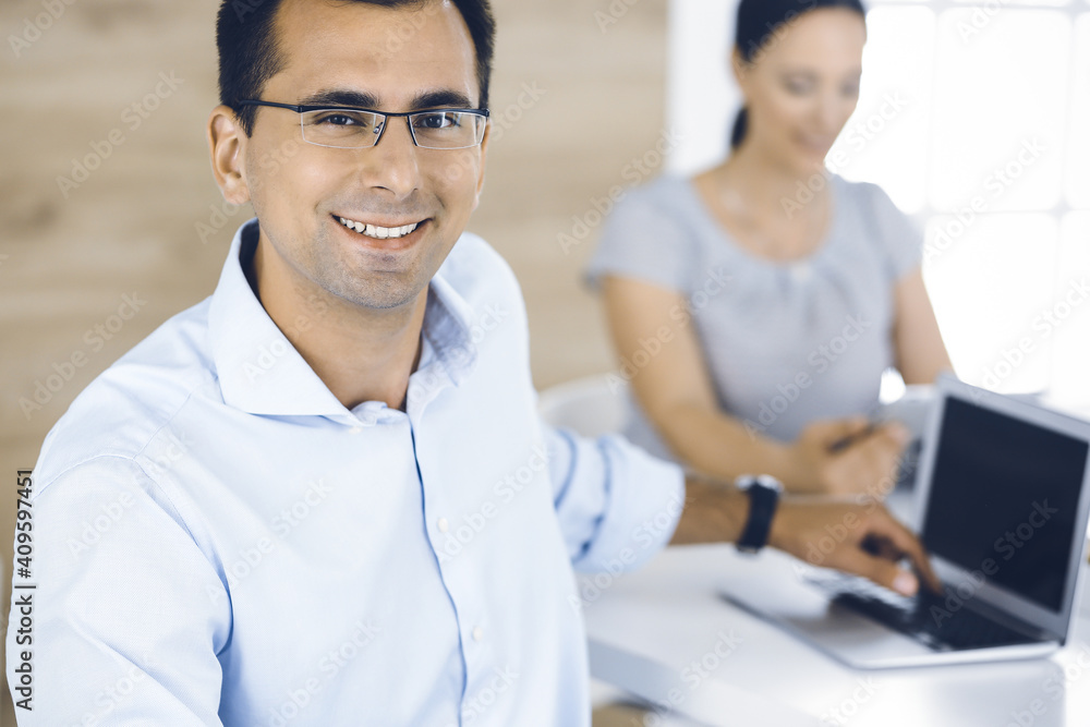 Businessman and business woman discussing questions while using a computer in modern office. Portrait of male entrepreneur at meeting. Group of diverse people Businessman and business woman discussing questions while using a computer in modern office. Portrait of male entrepreneur at meeting. Group of diverse people