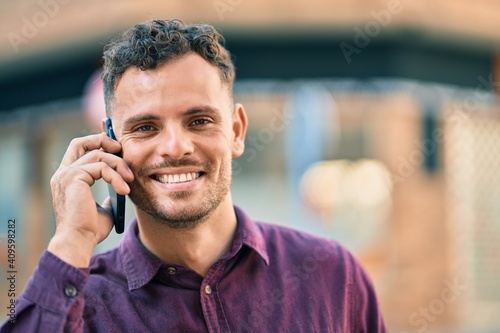 Young hispanic man smiling happy talking on the smartphone at the city.