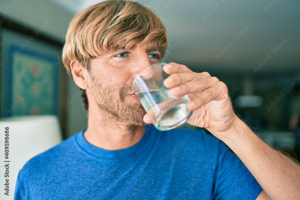 Young irish man drinking glass of water standing at home Young irish man drinking glass of water standing at home