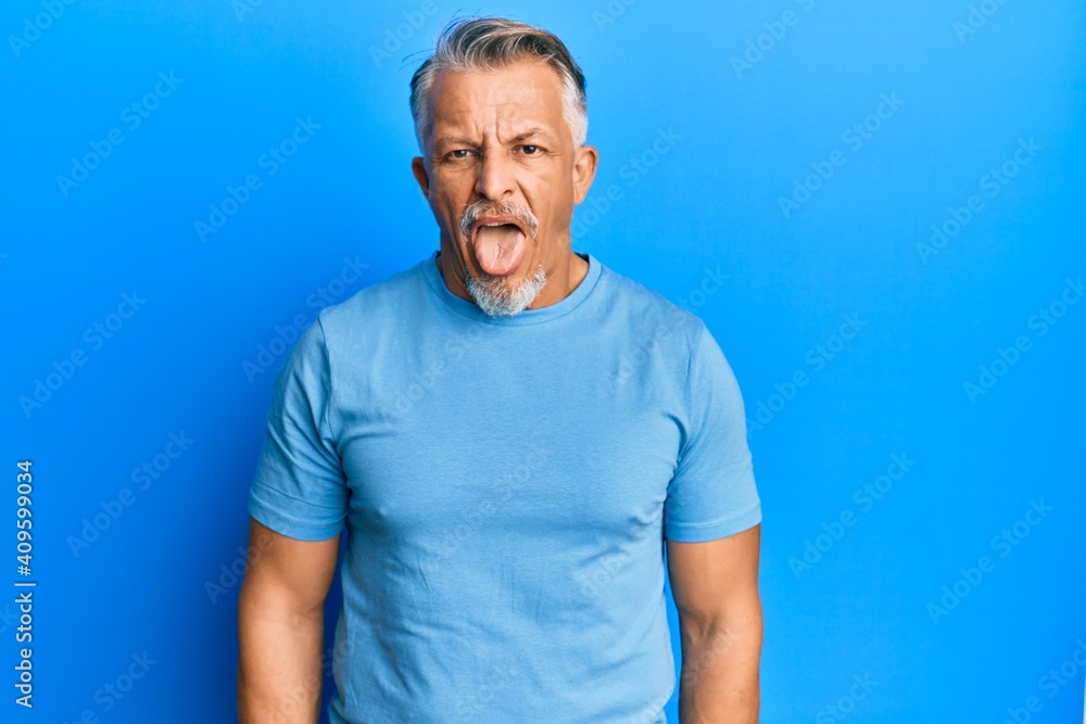 Fototapeta premium Middle age grey-haired man wearing casual clothes sticking tongue out happy with funny expression. emotion concept.