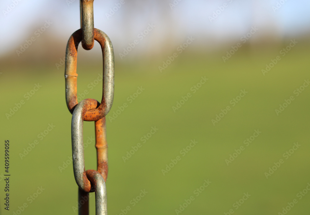 Image of vertical rusty chain with blurred rural background and space for copy Image of vertical rusty chain with blurred rural background and space for copy