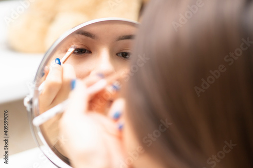 Young woman applies makeup looking in the mirror, paints her eyes with eye shadow