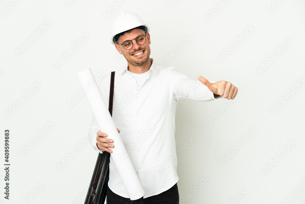 Young architect man with helmet and holding blueprints isolated on white background giving a thumbs up gesture Young architect man with helmet and holding blueprints isolated on white background giving a thumbs up gesture
