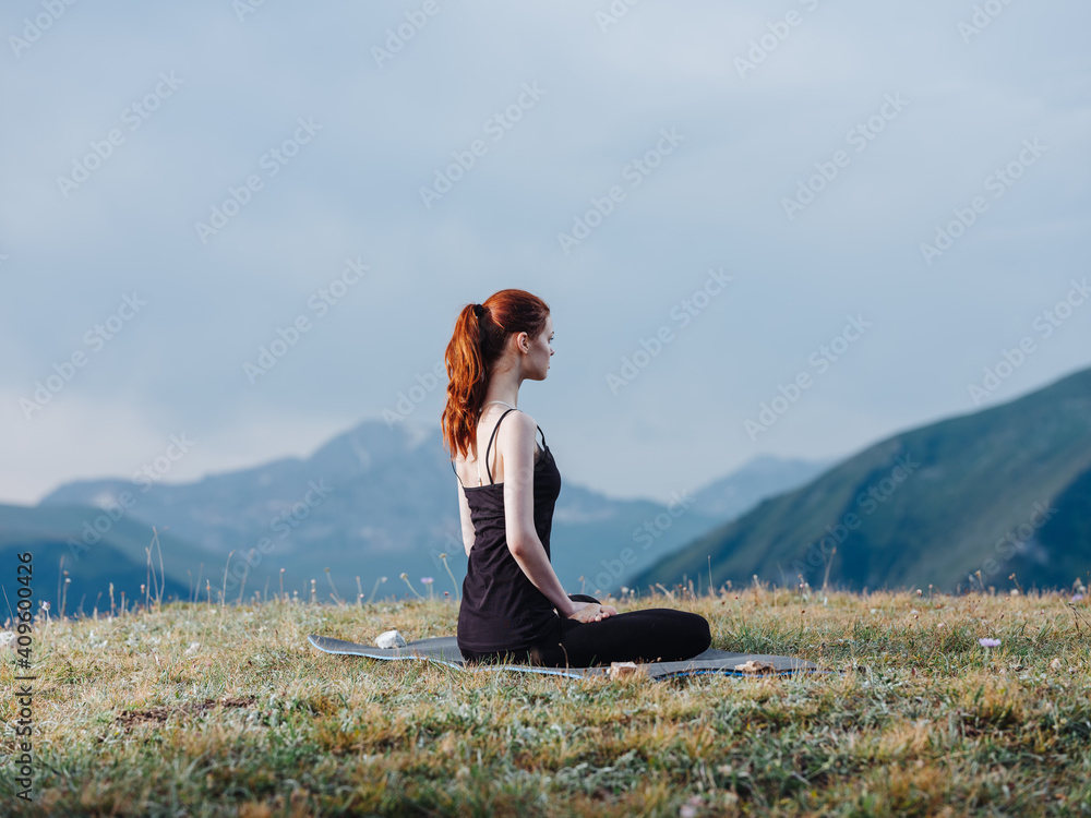A slender woman is engaged in yoga in nature in the mountains in leggings and a T-shirt