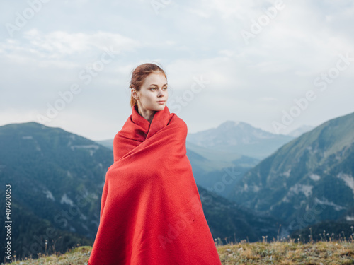 Red-haired woman with a plaid on her shoulders in the mountains on nature travel tourism