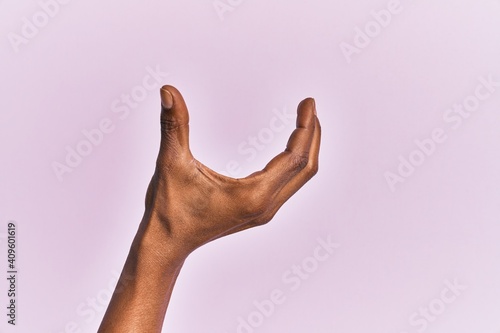 Arm and hand of black middle age woman over pink isolated background picking and taking invisible thing, holding object with fingers showing space photo