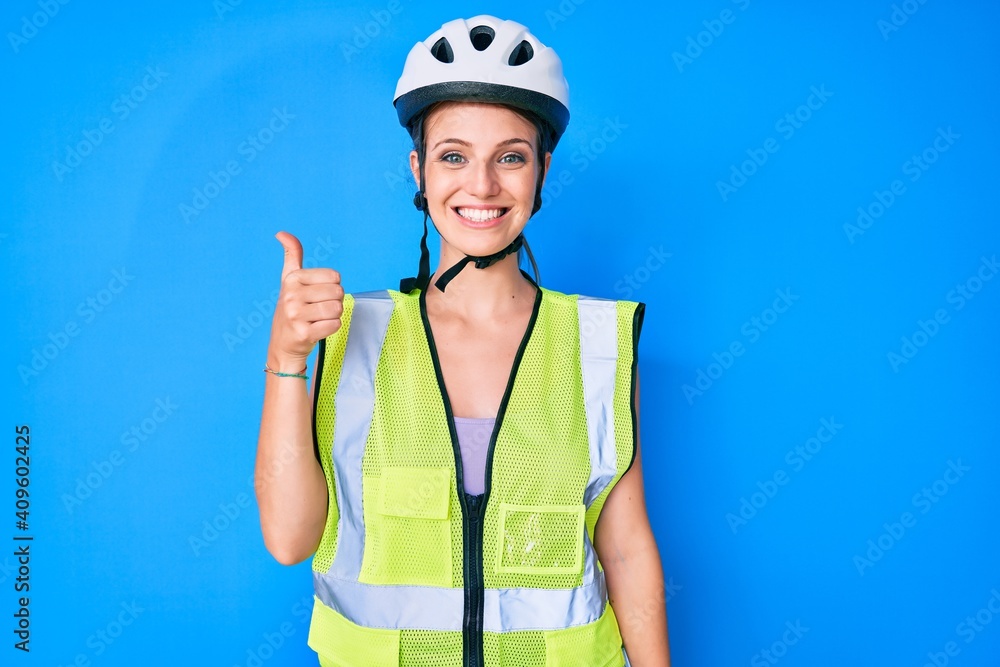 Young caucasian girl wearing bike helmet and reflective vest smiling happy and positive, thumb up doing excellent and approval sign Young caucasian girl wearing bike helmet and reflective vest smiling happy and positive, thumb up doing excellent and approval sign