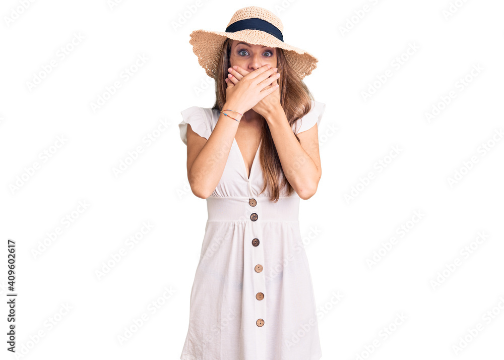 Young beautiful blonde woman wearing summer dress and hat shocked covering mouth with hands for mistake. secret concept. Young beautiful blonde woman wearing summer dress and hat shocked covering mouth with hands for mistake. secret concept.