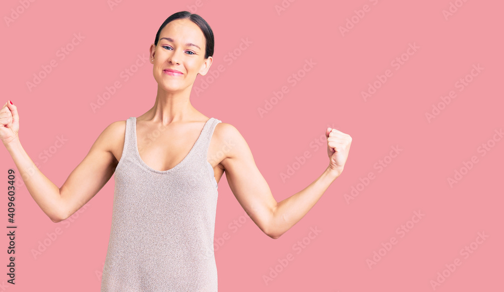Beautiful brunette young woman wearing casual dress very happy and excited doing winner gesture with arms raised, smiling and screaming for success. celebration concept. Beautiful brunette young woman wearing casual dress very happy and excited doing winner gesture with arms raised, smiling and screaming for success. celebration concept.