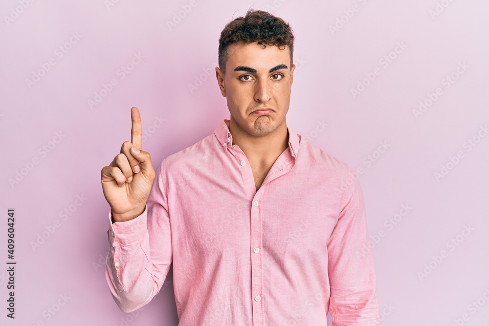 Hispanic young man pointing up with fingers depressed and worry for distress, crying angry and afraid. sad expression. Hispanic young man pointing up with fingers depressed and worry for distress, crying angry and afraid. sad expression.