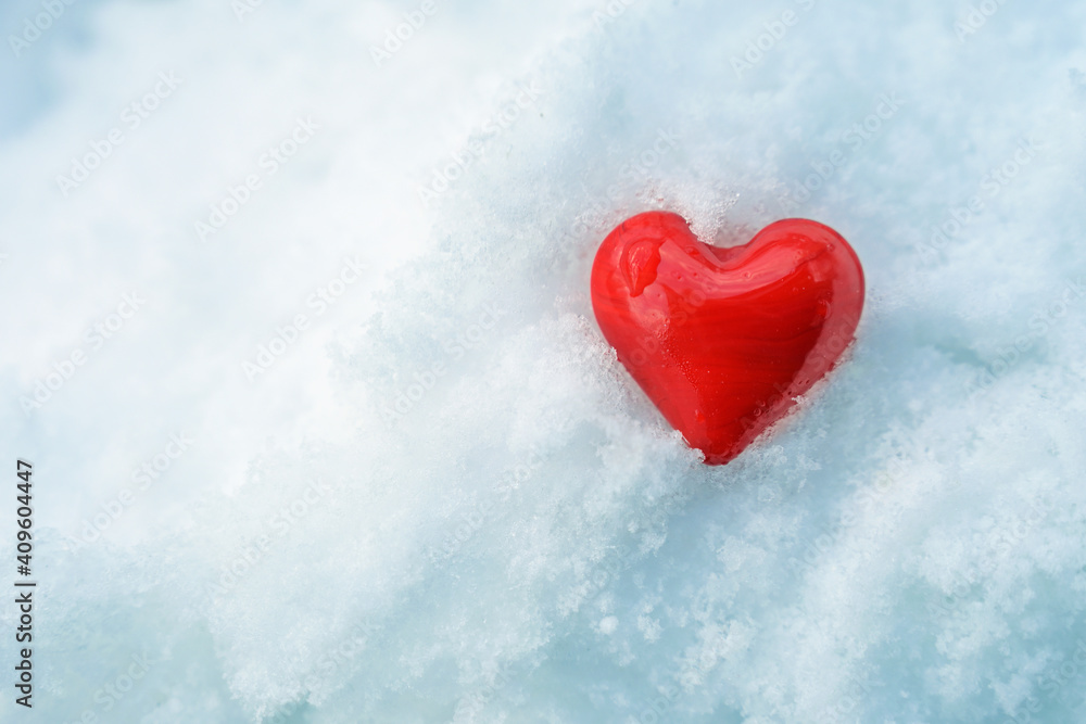 Heart shape made from red glass in the cold white snow, hot love symbol for seasonal holidays like valentines day or chrismas, copy space