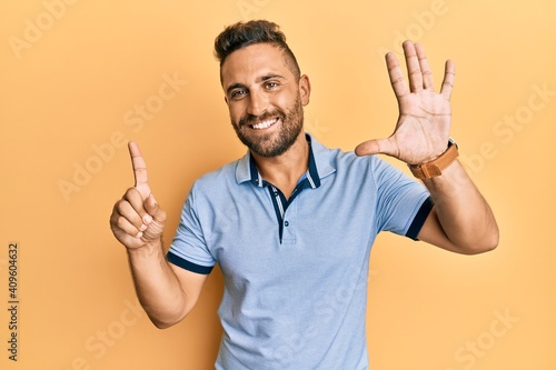 Handsome man with beard wearing casual clothes showing and pointing up with fingers number six while smiling confident and happy.