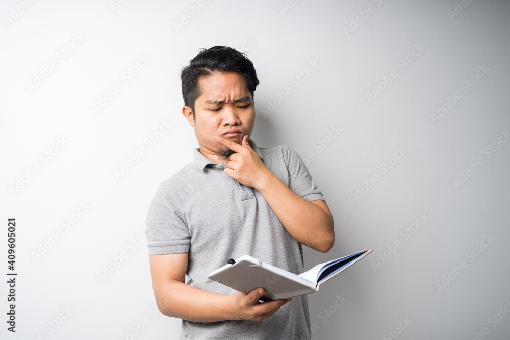 Portrait of Asian man holding book with face expression Portrait of Asian man holding book with face expression