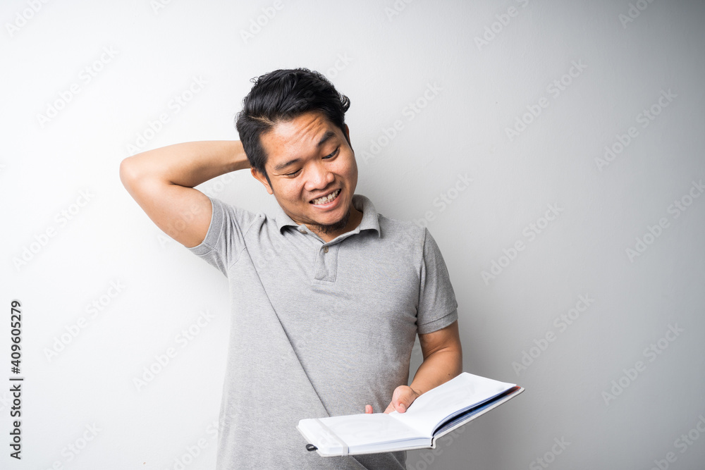 Portrait of Asian man holding book with face expression Portrait of Asian man holding book with face expression