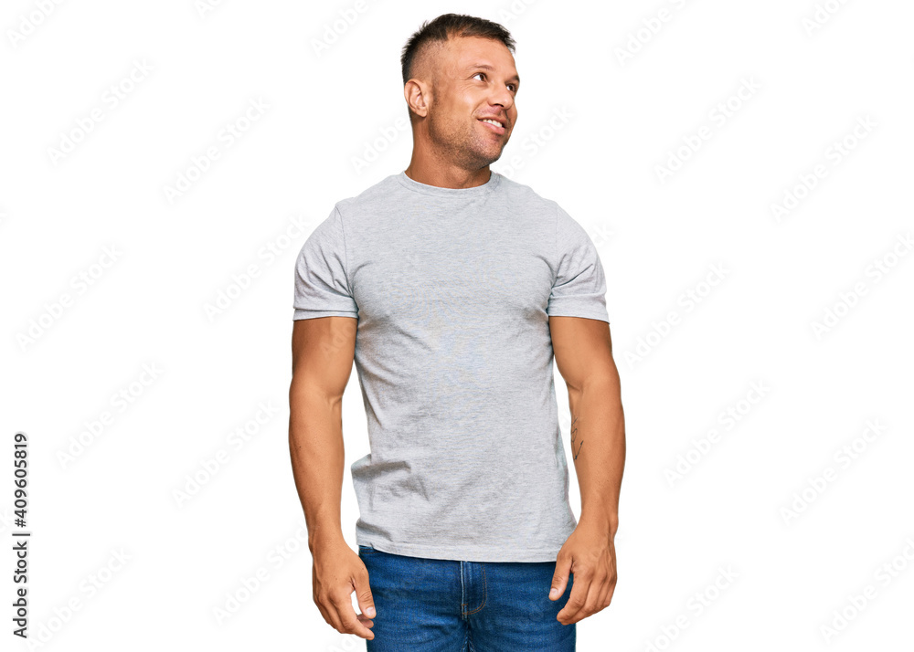 Handsome muscle man wearing casual grey tshirt looking away to side with smile on face, natural expression. laughing confident. Handsome muscle man wearing casual grey tshirt looking away to side with smile on face, natural expression. laughing confident.