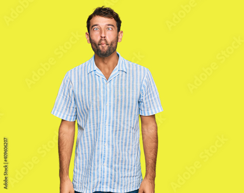 Handsome young man with beard wearing casual fresh shirt making fish face with lips, crazy and comical gesture. funny expression.