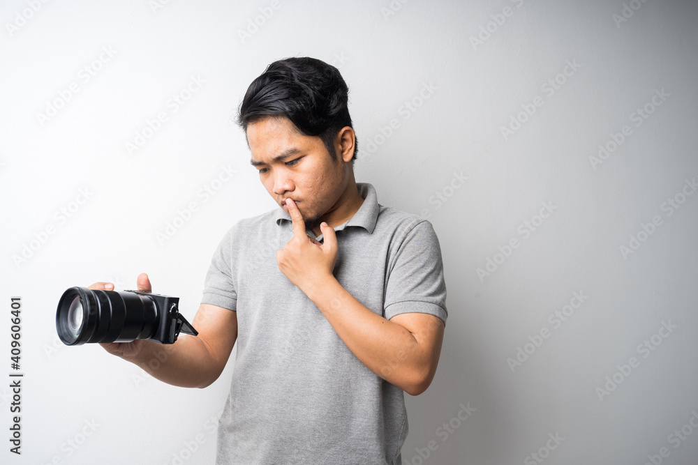 Young Asian man face expression with dslr or mirrorless camera. Photography, creative industry. Isolated selective focus. Young Asian man face expression with dslr or mirrorless camera. Photography, creative industry. Isolated selective focus.