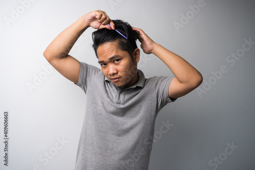 young Asian man comb his hair isolated selective focus