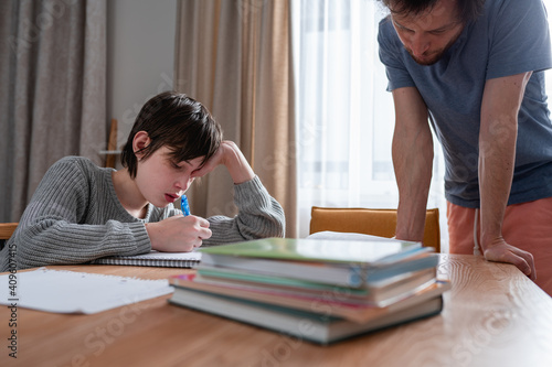 Teenager boy doing school lessons at home. Dad helping solve difficult math problems. Problems and difficulties of home education