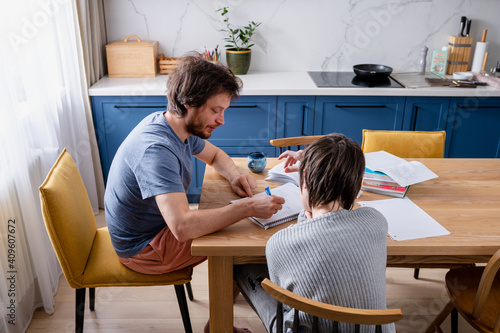 Teenager boy doing school lessons at home. Dad helping solve difficult math problems. Problems and difficulties of home education