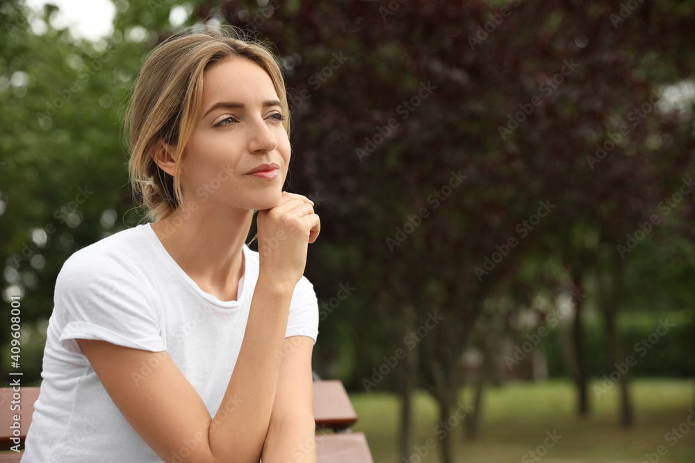 Beautiful young woman sitting on bench in park Beautiful young woman sitting on bench in park