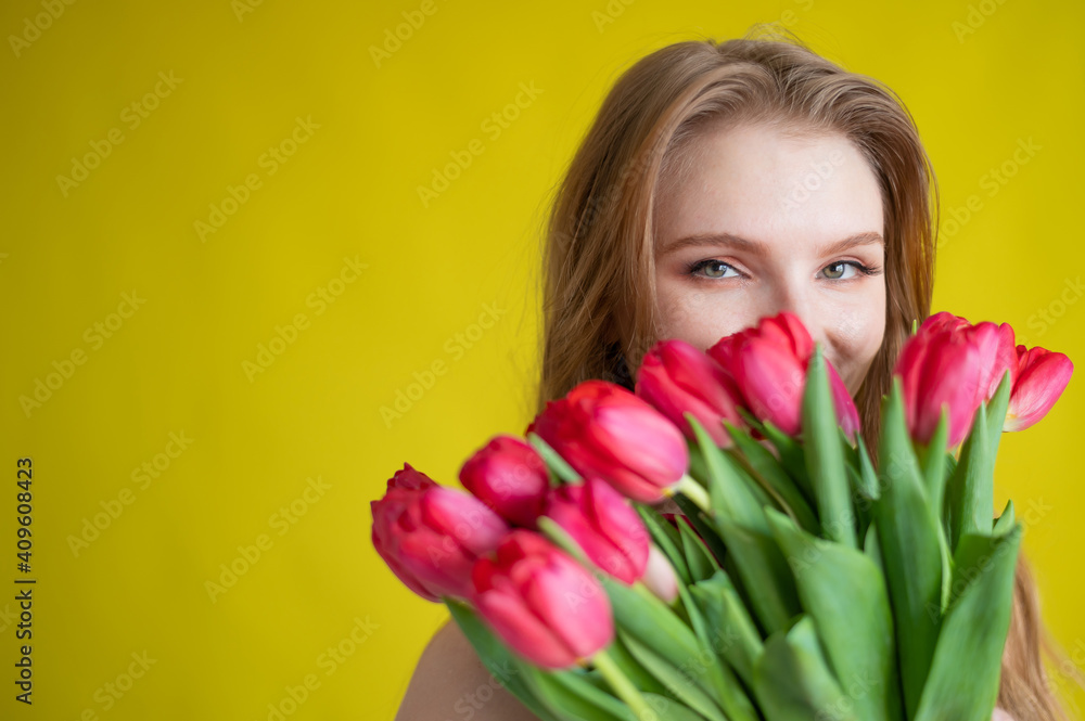 Woman with a bouquet of red tulips on a yellow background. Happy girl in a black dress holds an armful of flowers . Gift for Valentine's Day. The most romantic day of the year. Woman with a bouquet of red tulips on a yellow background. Happy girl in a black dress holds an armful of flowers . Gift for Valentine's Day. The most romantic day of the year.