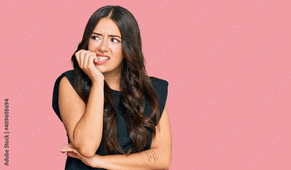 Beautiful brunette young woman wearing black shirt looking stressed and nervous with hands on mouth biting nails. anxiety problem. Beautiful brunette young woman wearing black shirt looking stressed and nervous with hands on mouth biting nails. anxiety problem.
