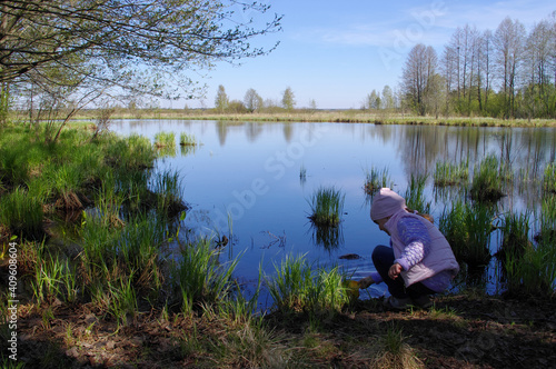 Fotografi A child is playing with water on a scenic lake edge (bank)