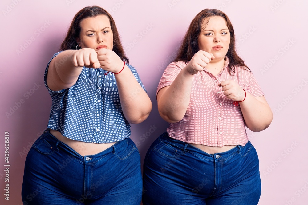 Young plus size twins wearing casual clothes punching fist to fight, aggressive and angry attack, threat and violence Young plus size twins wearing casual clothes punching fist to fight, aggressive and angry attack, threat and violence