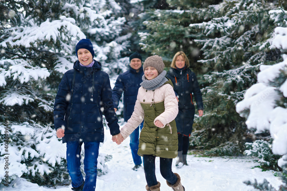 family walking in the winter forest, two parents and two children, beautiful nature with bright snowy fir trees family walking in the winter forest, two parents and two children, beautiful nature with bright snowy fir trees