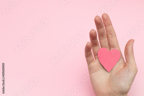 Red heart valentines cards in female hand on pink background  top view.