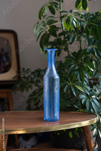 Mid century modern glass vase on a wooden table - in the background plants photo