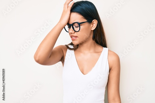 Young beautiful latin girl wearing casual clothes and glasses surprised with hand on head for mistake, remember error. forgot, bad memory concept.