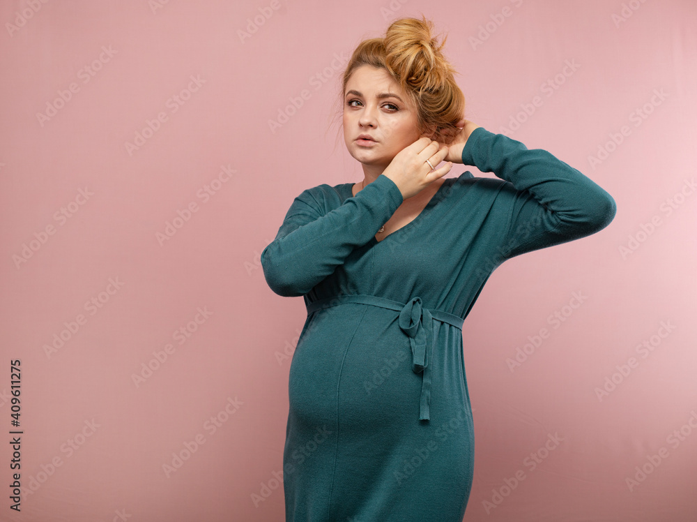 Portrait of a pregnant woman in a green dress on a pink background Portrait of a pregnant woman in a green dress on a pink background