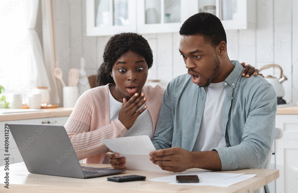 Shocked black couple in kitchen having financial problems, doing family budget calculations - obrazy, fototapety, plakaty 