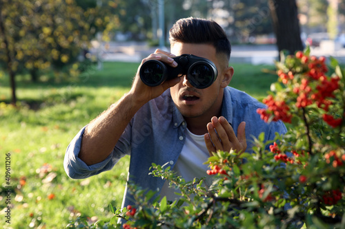 Slika na platnu Jealous man with binoculars spying on ex girlfriend in park